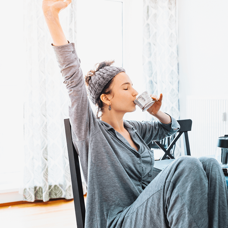 Femme profitant d'un moment de détente avec une boisson chaude, illustrant une routine matinale équilibrée avec L'Appart Fitness.