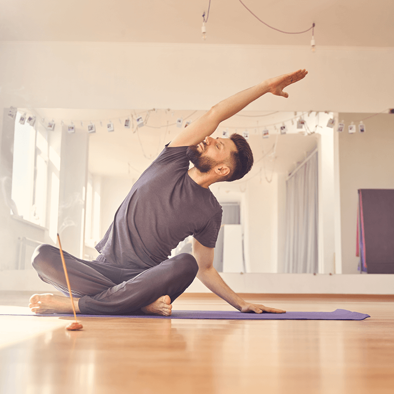 Un homme pratiquant des étirements matinaux dans un studio lumineux, parfait pour une routine matinale inspirée par L'Appart Fitness.